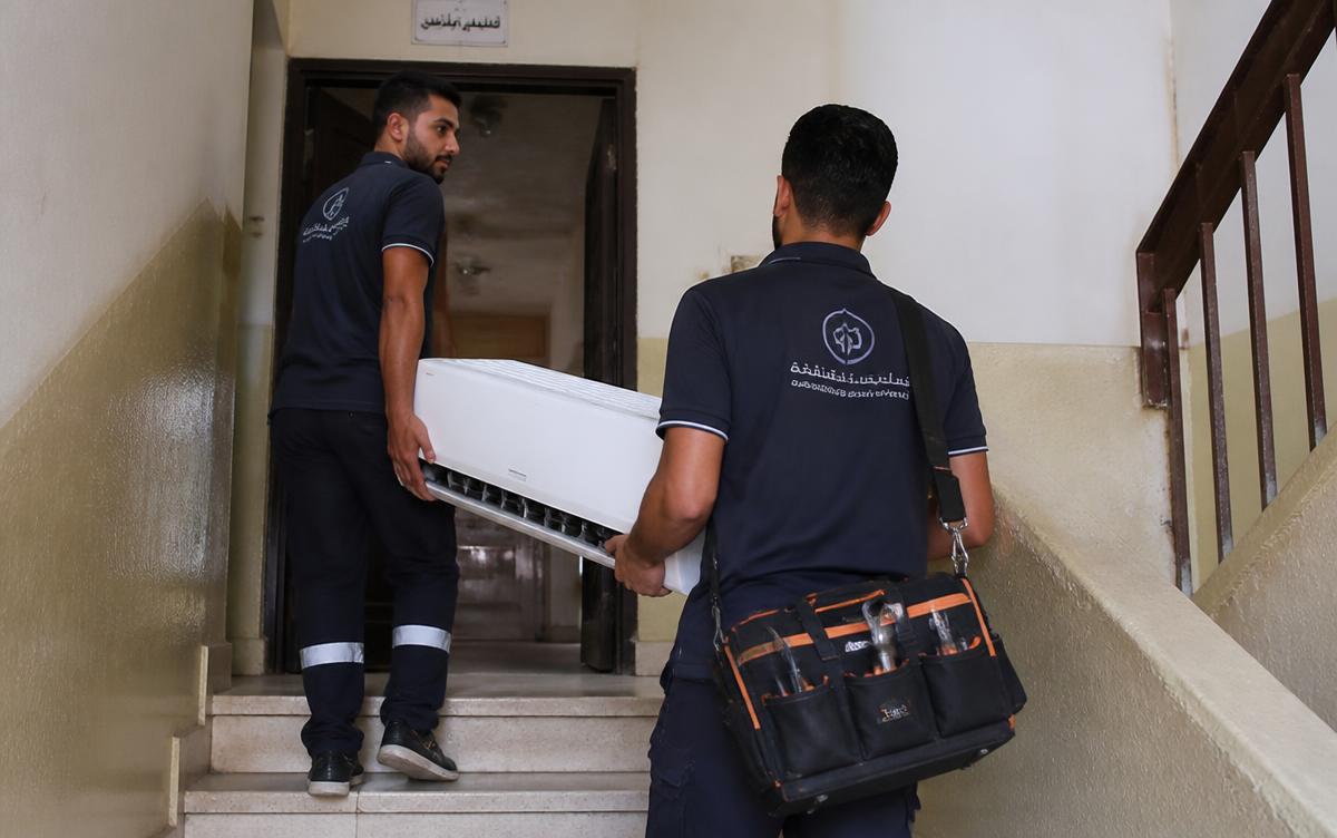 فنيا شركة الأمانة يحملان وحدة مكيف سبليت داخلية في سلّم عمارة سكنية بشرق الرياض